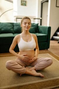 Photo by Yan Krukau Pregnant woman sitting cross-legged on a rug, with eyes closed and hands gently cradling her belly, symbolizing relaxation, mindfulness, and the success of infertility solutions.